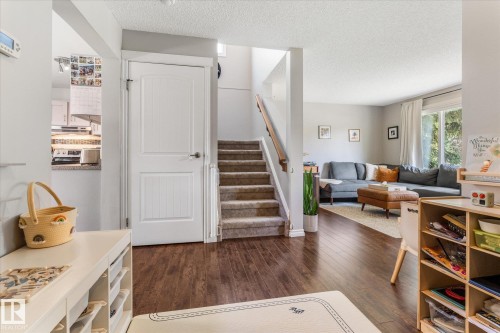 Inviting entryway featuring wood-finish flooring, a carpeted staircase with a wood handrail, and a clear sightline to the living area - 4718 35 Avenue Nw, Edmonton, AB - Indoor