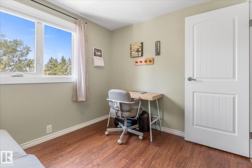 Bright room with a large window, wood-finish flooring, light-toned walls, white trim, and a paneled interior door - 4718 35 Avenue Nw, Edmonton, AB - Indoor