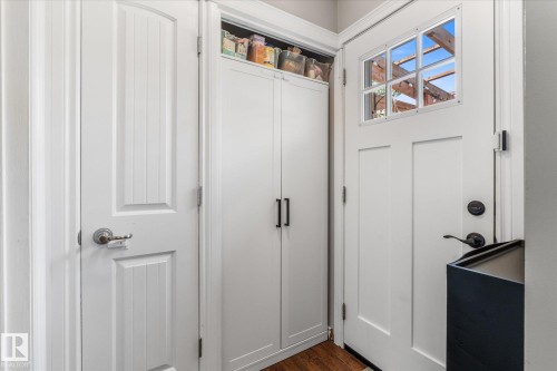 White paneled interior door, built-in storage cabinetry, wood-finish flooring, and exterior door with multi-pane window - 4718 35 Avenue Nw, Edmonton, AB - Indoor Photo Showing Other Room