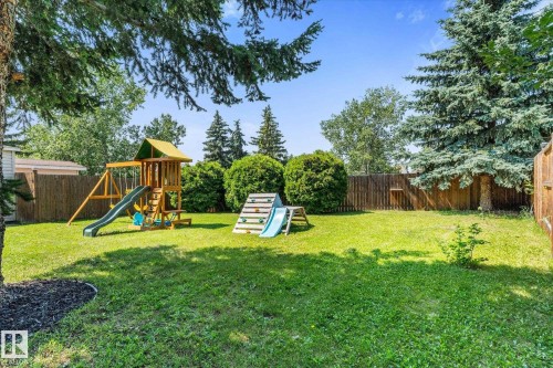 Expansive backyard featuring a lush green lawn, mature trees, and a privacy fence - 4718 35 Avenue Nw, Edmonton, AB - Outdoor With Backyard
