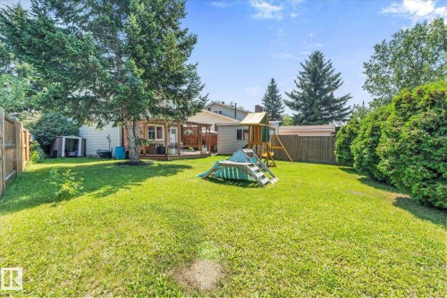 Expansive green lawn backyard featuring a wooden privacy fence and mature perimeter trees - 4718 35 Avenue Nw, Edmonton, AB - Outdoor With Backyard