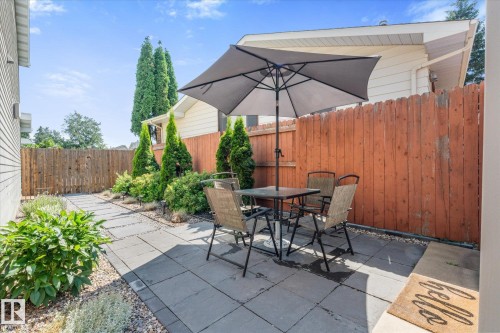 Private outdoor patio featuring large-format paver stones, a wooden privacy fence, and mature landscaping - 4718 35 Avenue Nw, Edmonton, AB - Outdoor With Deck Patio Veranda
