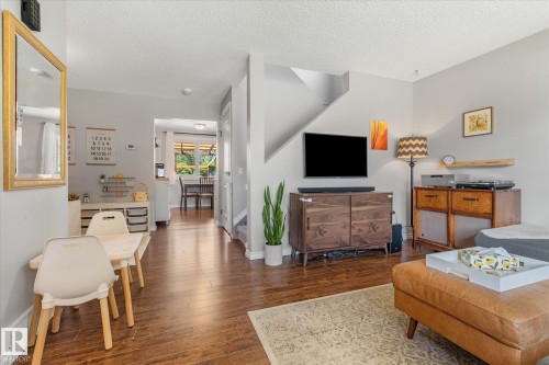 Open-concept living area featuring wood-finish flooring, light gray wall paint, and white baseboards - 4718 35 Avenue Nw, Edmonton, AB - Indoor