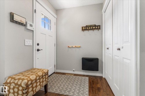 Entryway featuring wood-finish flooring, a white paneled door with frosted glass, and white bi-fold closet doors - 4718 35 Avenue Nw, Edmonton, AB - Indoor Photo Showing Other Room