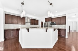 Kitchen island with white base and granite countertop, featuring dark wood-finish cabinetry, stainless steel appliances, and wood-finish flooring - 