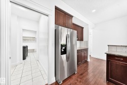 Kitchen featuring stainless steel appliances, wood-finish flooring, and dark wood cabinetry with granite countertops - 