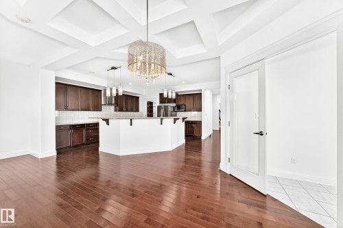 Open-concept living space featuring wood-finish flooring, a coffered ceiling, and a prominent crystal chandelier - 1663 Rutherford Road Sw, Edmonton, AB - Indoor Photo Showing Kitchen