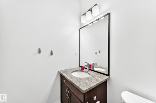 Bathroom vanity featuring a dark wood-finish cabinet with silver hardware, a light-toned stone countertop, and an undermount sink - 1663 Rutherford Road Sw, Edmonton, AB - Indoor Photo Showing Bathroom