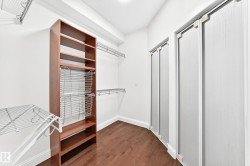 Walk-in closet featuring wood-finish flooring, built-in shelving, wire rack organizers, chrome hanging rods, and bi-fold closet doors - 