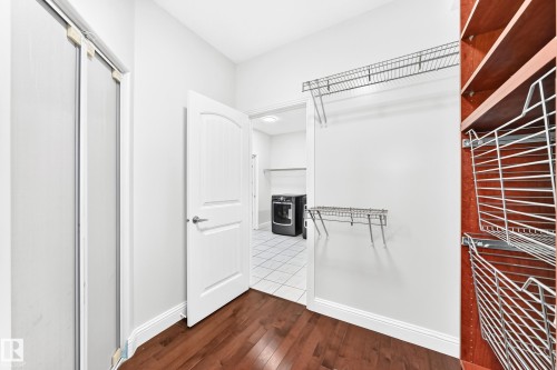 Expansive closet with rich wood-finish flooring, white walls, and a white arched panel door - 1663 Rutherford Road Sw, Edmonton, AB - Indoor