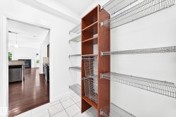 Pantry featuring white tile flooring, extensive wire shelving, a built-in wood-finish shelving unit, and integrated wire baskets - 