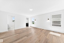 Spacious interior featuring wood-finish flooring, white walls, multiple windows, recessed lighting, and wall sconces - 