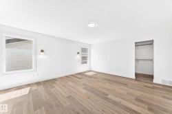 Spacious room featuring light wood-finish flooring, white walls, and a clean white ceiling - 