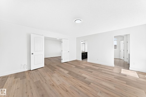 Spacious room featuring wood-finish flooring, white walls, and a contemporary ceiling light fixture - 1663 Rutherford Road Sw, Edmonton, AB - Indoor Photo Showing Other Room
