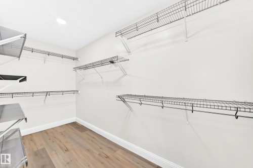 Spacious closet featuring multiple levels of wire shelving, integrated hanging rods, recessed ceiling lighting, light wood-finish flooring, and white baseboards - 1663 Rutherford Road Sw, Edmonton, AB - Indoor With Storage