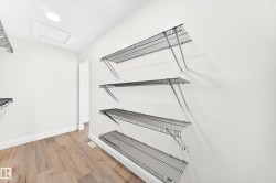 Utility room featuring wood-finish flooring, white walls, recessed ceiling lighting, and wire shelving - 