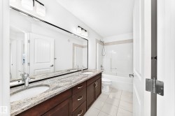 Bathroom featuring a double vanity with stone countertop, undermount sinks, chrome fixtures, and dark wood cabinetry - 
