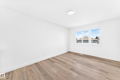 Spacious room featuring wood-finish flooring, white baseboards, and a three-pane window - 1663 Rutherford Road Sw, Edmonton, AB - Indoor Photo Showing Other Room