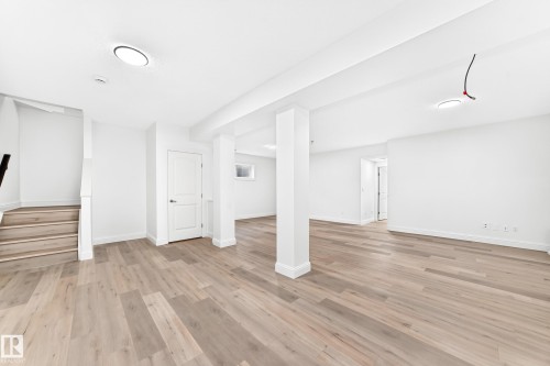 Open-concept lower level featuring light wood-finish flooring, white painted walls, recessed lighting, and a window - 1663 Rutherford Road Sw, Edmonton, AB - Indoor Photo Showing Other Room