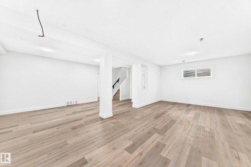 Spacious room featuring wood-finish flooring, white walls, and recessed lighting - 1663 Rutherford Road Sw, Edmonton, AB - Indoor