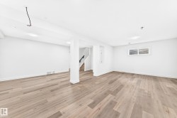 Spacious room featuring wood-finish flooring, white walls, and recessed lighting - 