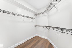 Walk-in closet featuring light wood-finish flooring, white baseboards, and white painted walls - 