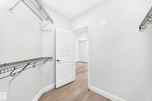 Walk-in closet featuring light wood-finish flooring, white baseboards, and multiple wire shelving units - 1663 Rutherford Road Sw, Edmonton, AB - Indoor
