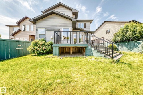 Spacious backyard featuring a multi-level deck with black metal railings, a privacy fence, and a large grassy area - 1663 Rutherford Road Sw, Edmonton, AB - Outdoor With Deck Patio Veranda