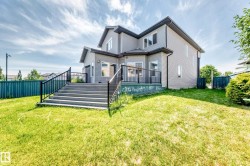 Spacious backyard featuring a multi-level deck with dark railings and steps, light gray siding, and a dark shingle roof - 