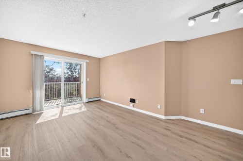 Spacious room featuring light wood-finish flooring and neutral-toned walls - #317 245 Edwards Dr Sw, Edmonton, AB - Indoor Photo Showing Other Room