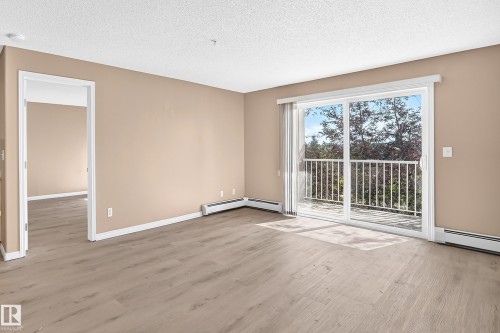 Spacious room featuring wood-finish flooring and a neutral color palette - #317 245 Edwards Dr Sw, Edmonton, AB - Indoor Photo Showing Other Room