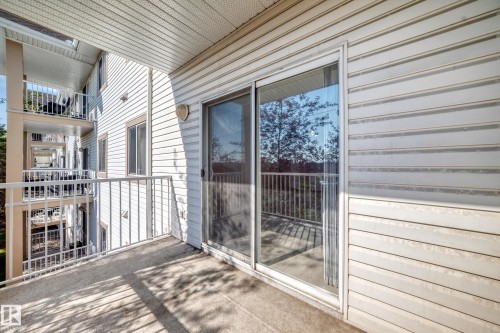 Private balcony with a sliding glass door entry, concrete flooring, and white metal railings - #317 245 Edwards Dr Sw, Edmonton, AB - Outdoor With Balcony With Exterior