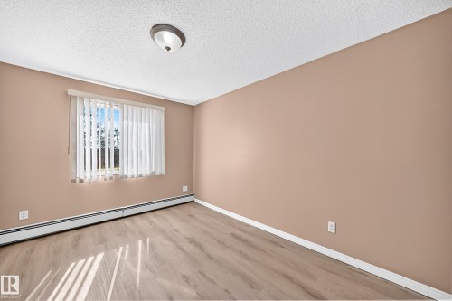Room with wood-finish flooring, a window featuring vertical blinds, and a neutral wall color - #317 245 Edwards Dr Sw, Edmonton, AB - Indoor Photo Showing Other Room