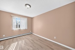 Room with wood-finish flooring, a window featuring vertical blinds, and a neutral wall color - 