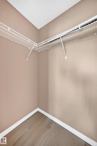 Interior storage space featuring wood-finish flooring, white baseboards, light-toned wall paint, and white wire shelving - #317 245 Edwards Dr Sw, Edmonton, AB - Indoor With Storage