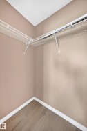 Interior storage space featuring wood-finish flooring, white baseboards, light-toned wall paint, and white wire shelving - 