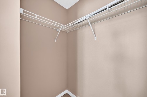 Corner closet featuring wire shelving and hanging rods, neutral wall tones, and white baseboards - #317 245 Edwards Dr Sw, Edmonton, AB - Indoor With Storage