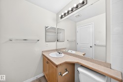 Neutral-toned bathroom featuring a wood-finish vanity with a single basin sink and a light-colored countertop - 