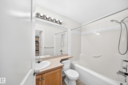 Full bathroom featuring a single vanity with wood cabinetry, a light-colored countertop, and a white integrated sink - #317 245 Edwards Dr Sw, Edmonton, AB - Indoor Photo Showing Bathroom
