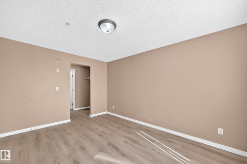 Spacious room featuring wood-finish flooring and neutral wall tones - #317 245 Edwards Dr Sw, Edmonton, AB - Indoor Photo Showing Other Room