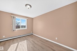 Windowed room featuring wood-finish flooring, neutral wall tones, baseboard heating, and a ceiling-mounted light fixture - 