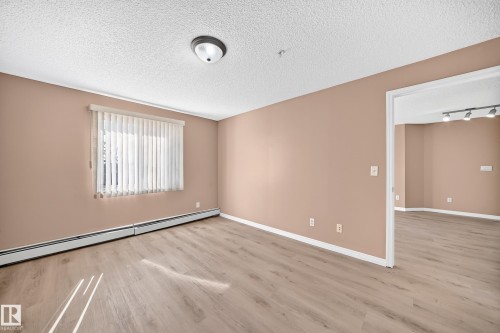 Spacious room featuring wood-finish flooring and a neutral color palette - #317 245 Edwards Dr Sw, Edmonton, AB - Indoor Photo Showing Other Room