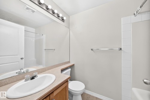 Bathroom featuring a single vanity with an oval basin, a large wall mirror, and a toilet - #317 245 Edwards Dr Sw, Edmonton, AB - Indoor Photo Showing Bathroom