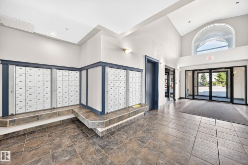 Entry foyer featuring high vaulted ceilings, large arched window, and durable tile flooring - #317 245 Edwards Dr Sw, Edmonton, AB - Indoor Photo Showing Other Room