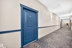 Apartment entry featuring a vibrant blue door with paneling, complementary blue trim, and a contemporary wall sconce - 