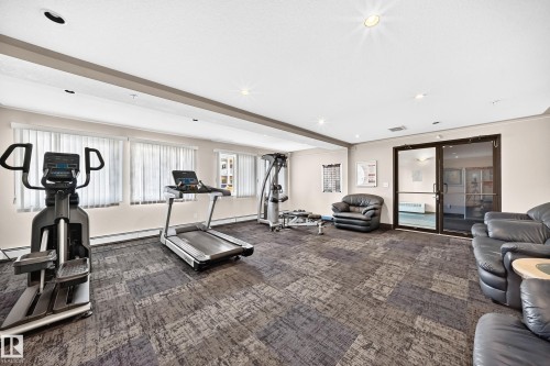 Fitness room featuring patterned carpet, multiple windows with blinds, recessed lighting, and a glass-paneled door - #317 245 Edwards Dr Sw, Edmonton, AB - Indoor Photo Showing Gym Room