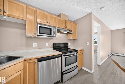 Kitchen featuring light wood cabinetry, stainless steel appliances, an over-the-range microwave, and light-toned countertops - #317 245 Edwards Dr Sw, Edmonton, AB - Indoor Photo Showing Kitchen