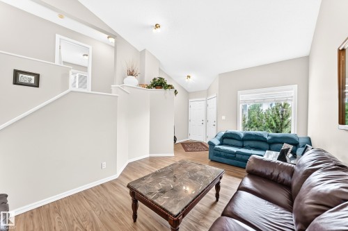 Open-concept living area featuring wood-finish flooring, vaulted ceilings, and natural light from a large window - 3226 30 Avenue Nw, Edmonton, AB - Indoor Photo Showing Other Room