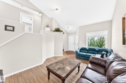 Open-concept living area featuring wood-finish flooring, vaulted ceilings, and natural light from a large window - 