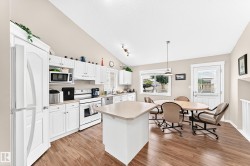 Open-concept kitchen and dining area featuring vaulted ceilings, wood-finish flooring, white cabinetry, a kitchen island, and a glass-paneled back door - 